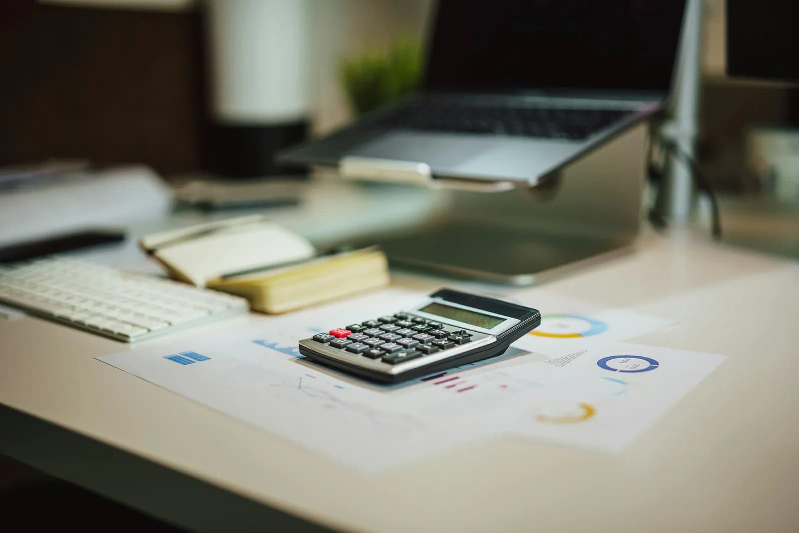 Desk with documents, a calculator and a laptop